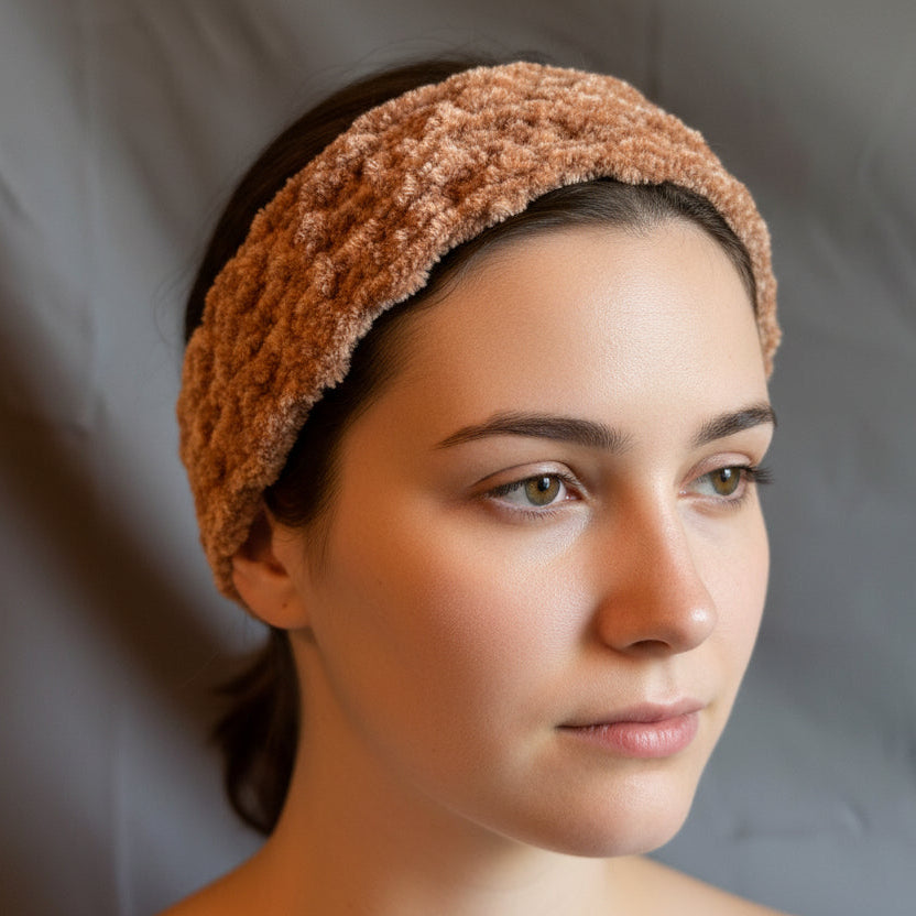 Woman wearing a tan crocheted headband against a neutral background