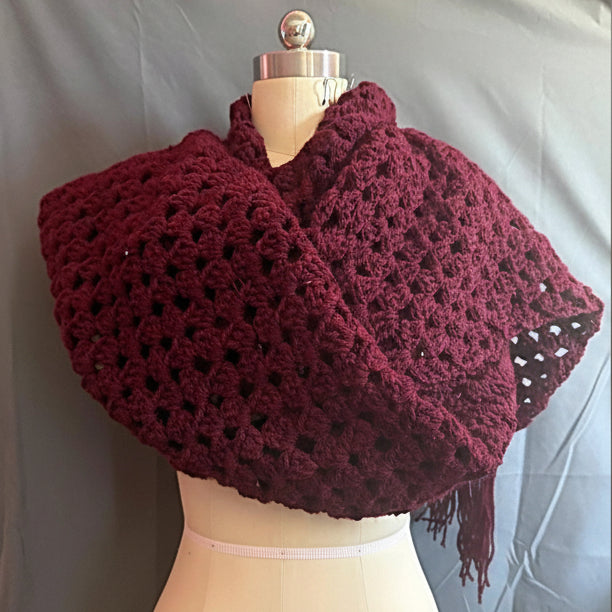 Burgundy crocheted over sized wrap on a mannequin against a plain background