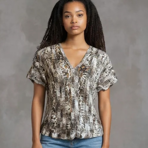 Woman wearing a patterned crocheted blouse against a gray background