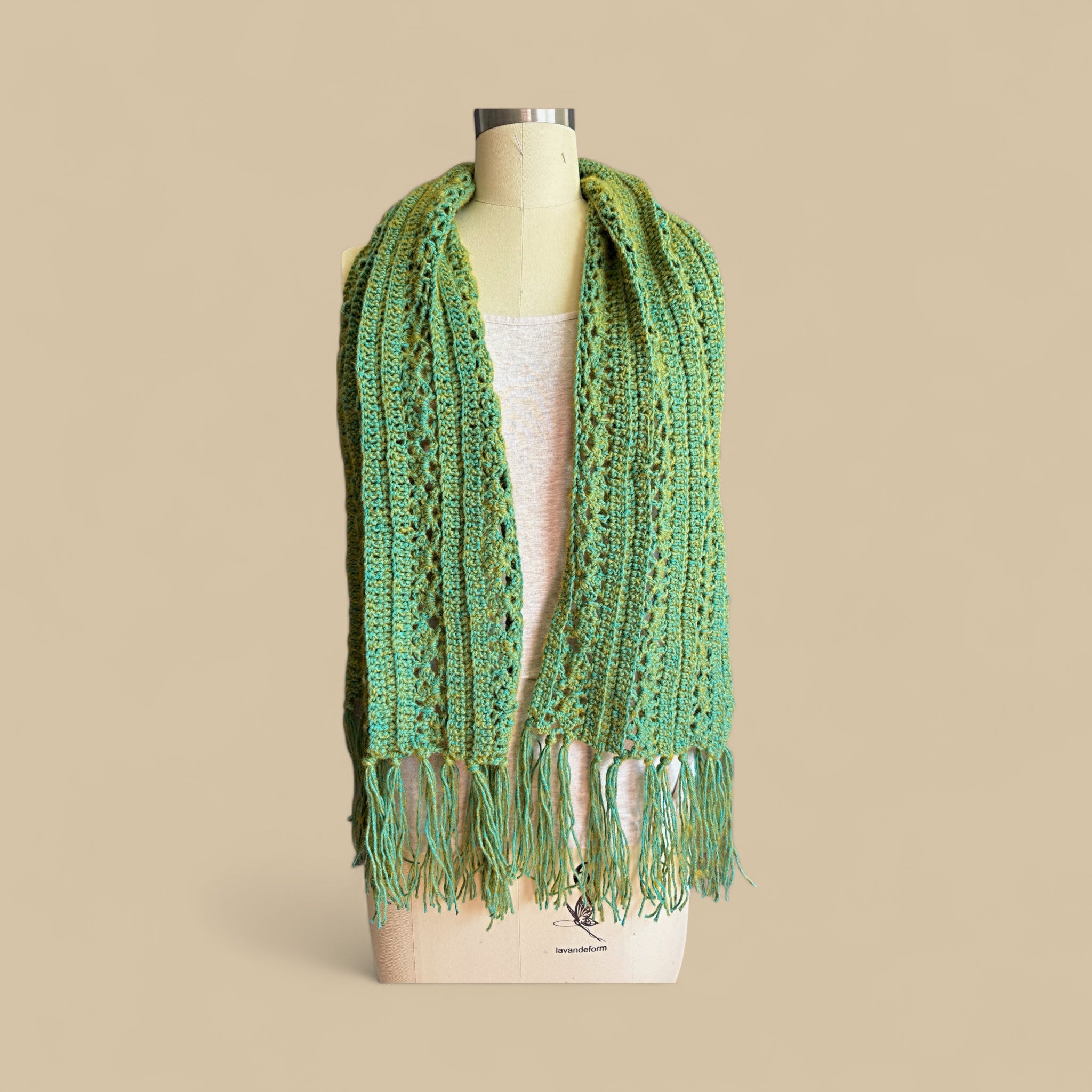 Moss Green crocheted lace scarf with fringe on a mannequin against a beige background