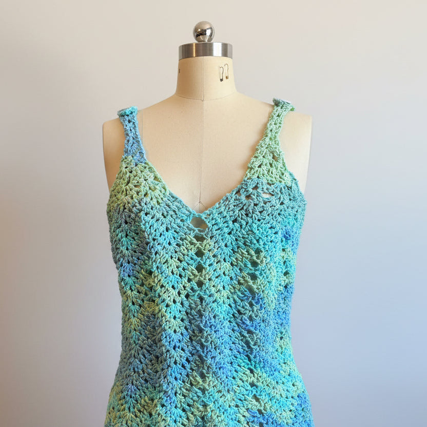 Crocheted tank top with gradient blue and green colors on a mannequin against a dark background