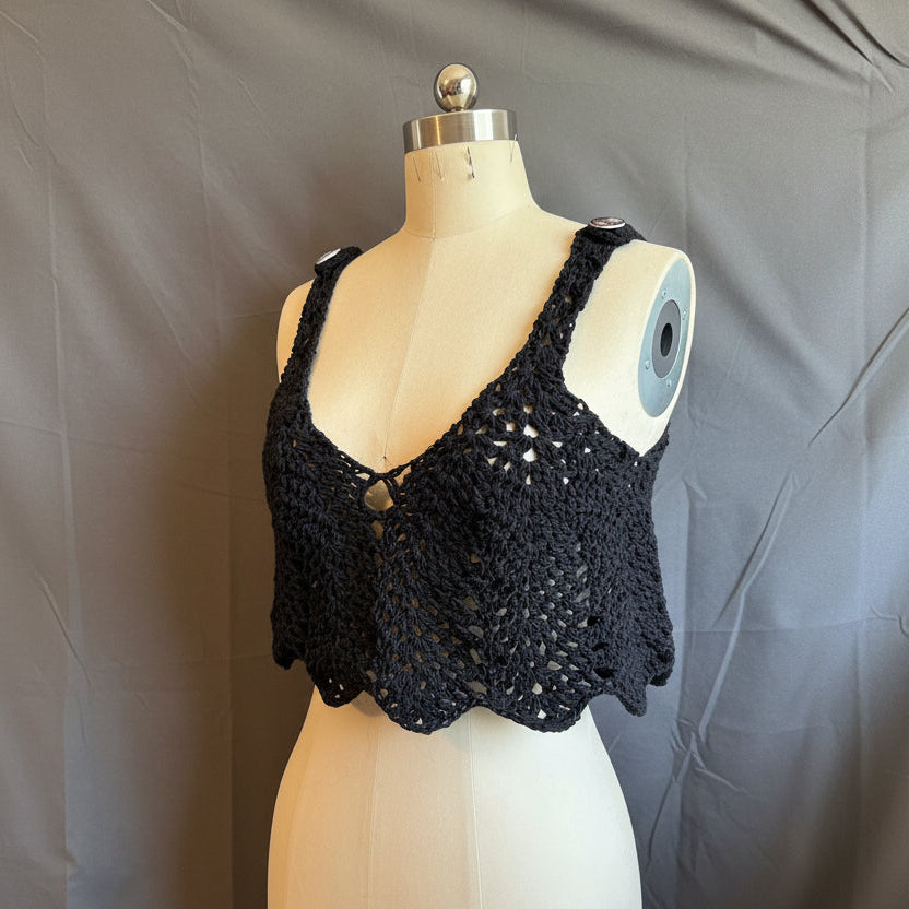 Black crochet top on a mannequin against a gray background