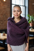 Woman wearing a oversized fuchsia and black crocheted shawl in an indoor setting.