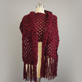 Maroon crocheted over sized wrap with fringe on a mannequin against a gray background