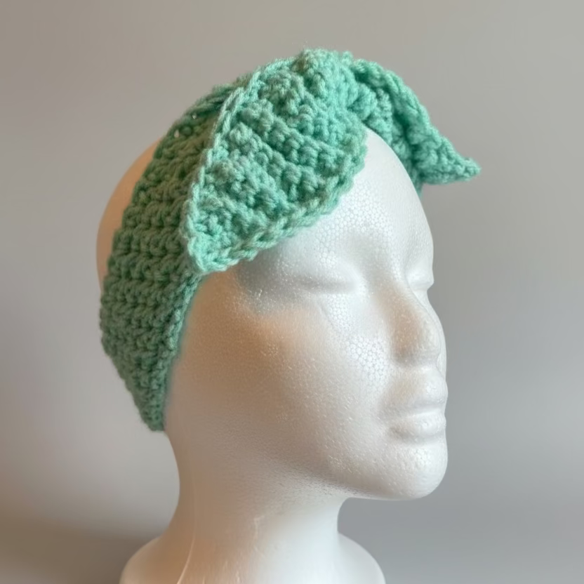Mint Green crocheted headband on a mannequin head against a plain background
