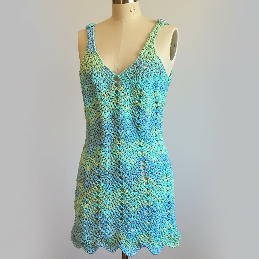 Crocheted dress with a gradient of blue and green on a mannequin against a light grey background