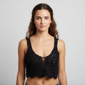 Woman wearing a black crochet top against a plain background